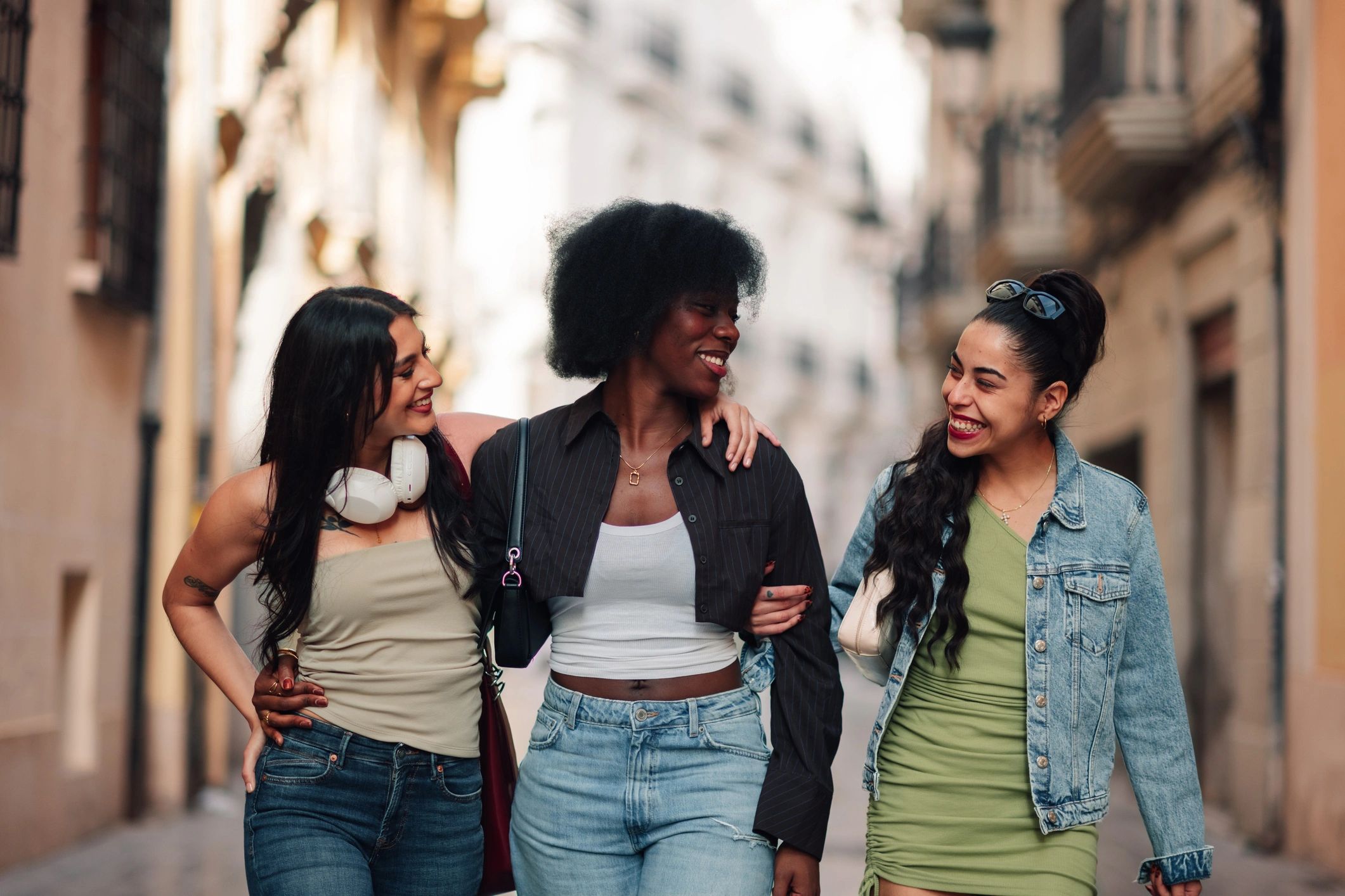 Three friends laughing together on a city street
